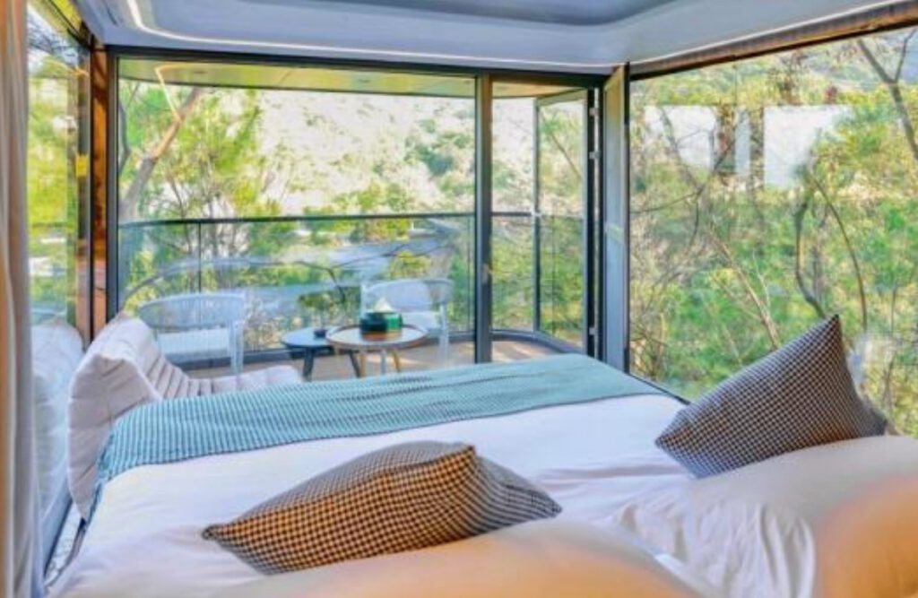 A bedroom with a view of the trees and a deck.